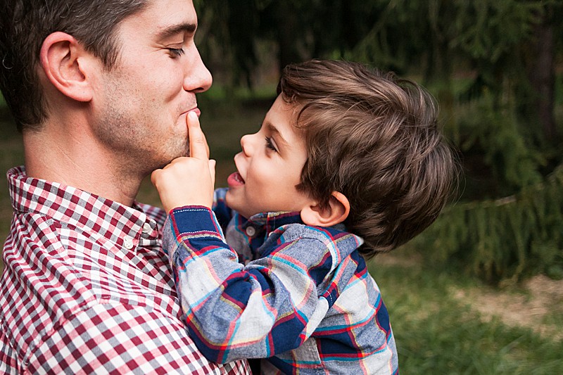 Toddler son looking up at his dad touching his mouth