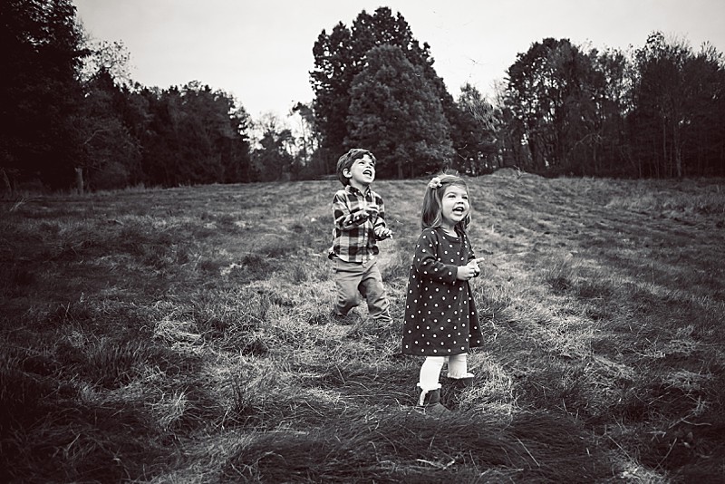Black and white image of two toddler children playing in a big field